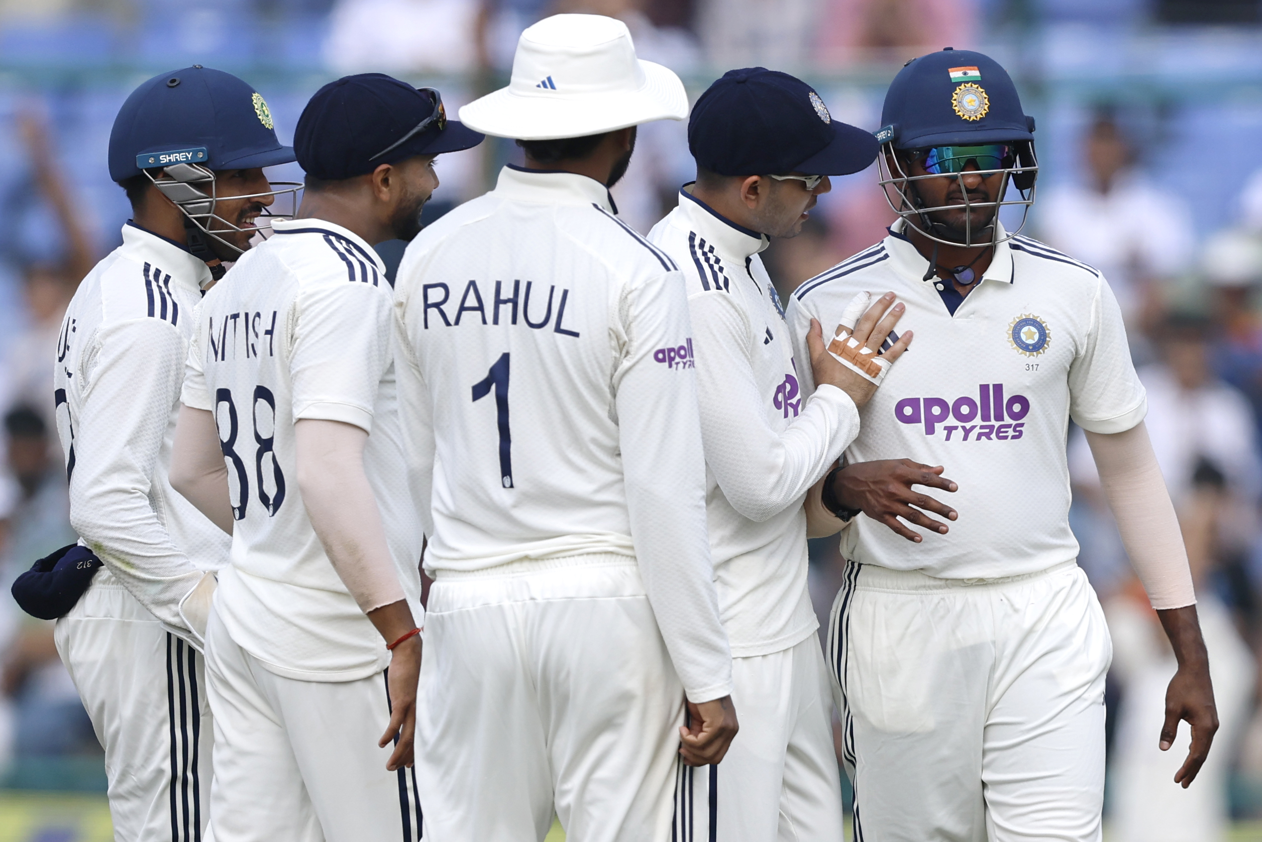Teammates attending to Sai Sudharsan after he injured his hand while taking a catch against the West Indies in Delhi.
